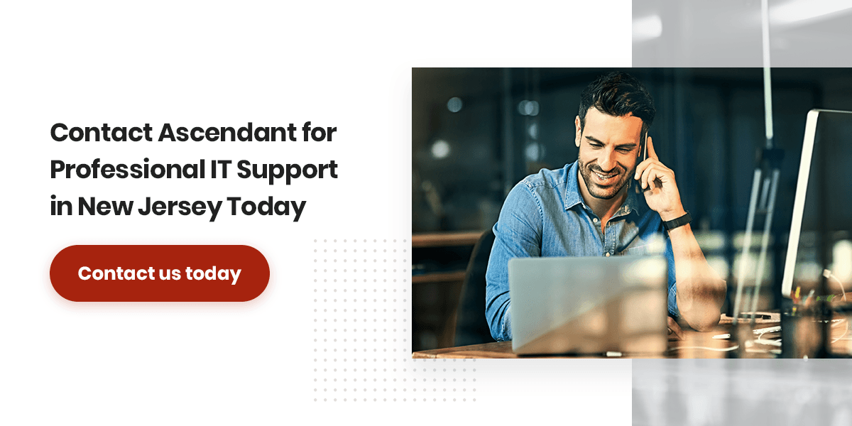 A man sitting at a desk talking on a cell phone with directions to call Ascendant for NJ IT support